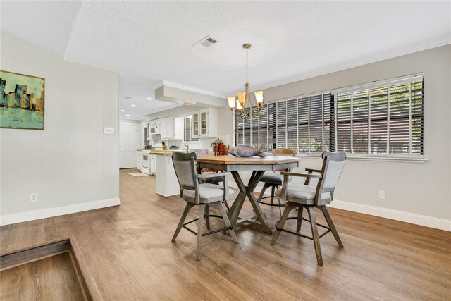 dining room featuring visible vents, crown molding, and light wood-style floors