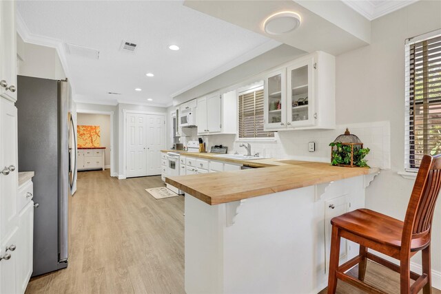 kitchen featuring a sink, backsplash, white appliances, crown molding, and wooden counters