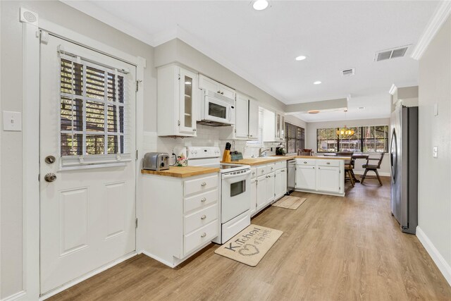 kitchen featuring visible vents, a peninsula, white cabinets, appliances with stainless steel finishes, and backsplash