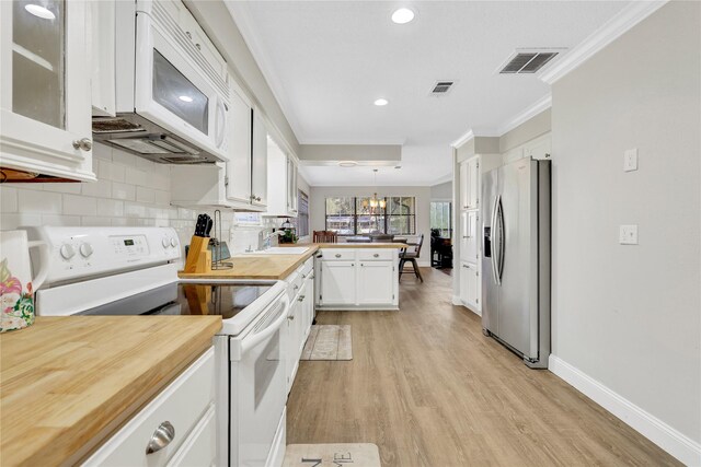 kitchen with white appliances, visible vents, a peninsula, ornamental molding, and white cabinetry