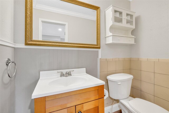 bathroom featuring wainscoting, crown molding, toilet, and vanity