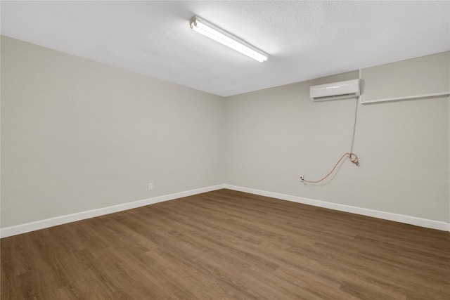 basement featuring an AC wall unit, wood finished floors, and baseboards