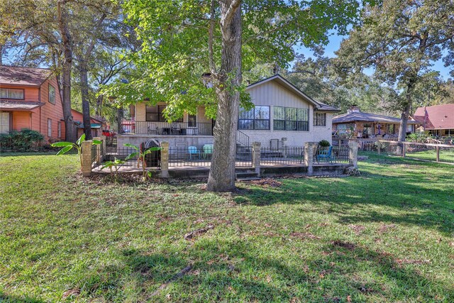 rear view of property featuring brick siding, a lawn, and fence