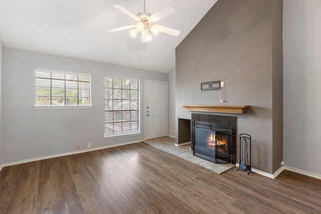 unfurnished living room with ceiling fan, a fireplace, vaulted ceiling, and light wood-type flooring