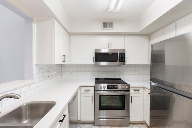 kitchen with decorative backsplash, sink, white cabinets, and appliances with stainless steel finishes