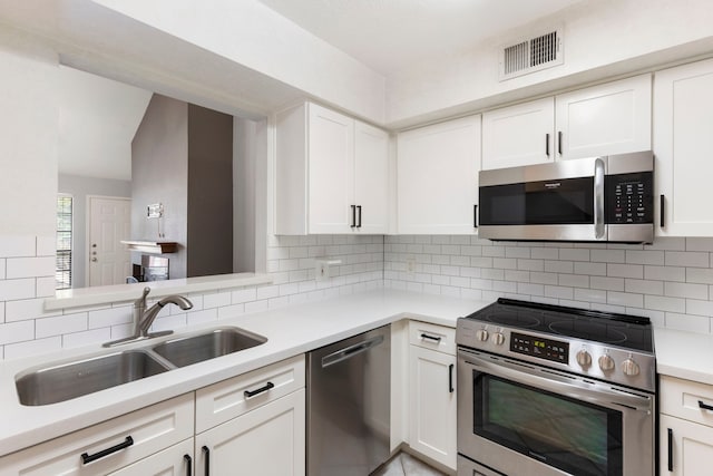 kitchen with tasteful backsplash, sink, white cabinets, and stainless steel appliances