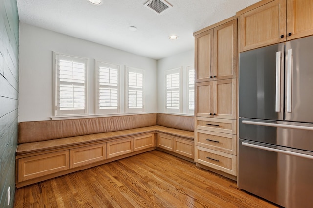 kitchen featuring stainless steel fridge, light brown cabinetry, a textured ceiling, and light wood-type flooring