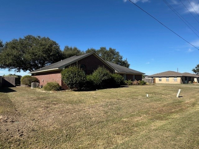 view of side of property with a lawn and central AC