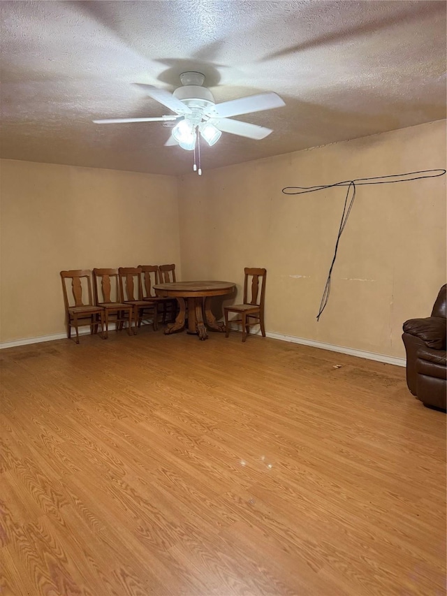 interior space with ceiling fan, light wood-type flooring, and a textured ceiling