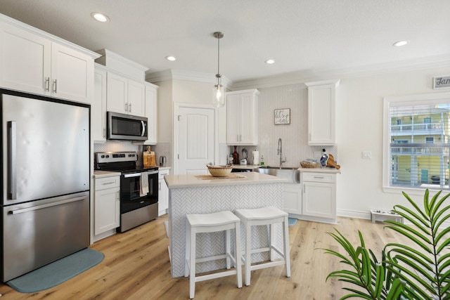 kitchen featuring white cabinets, pendant lighting, stainless steel appliances, and light hardwood / wood-style flooring