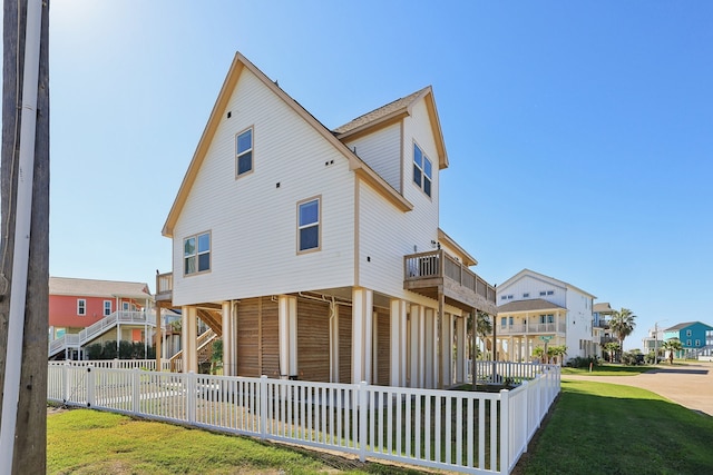 back of house featuring a lawn and a balcony