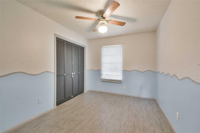 spare room featuring ceiling fan, light hardwood / wood-style floors, and a textured ceiling