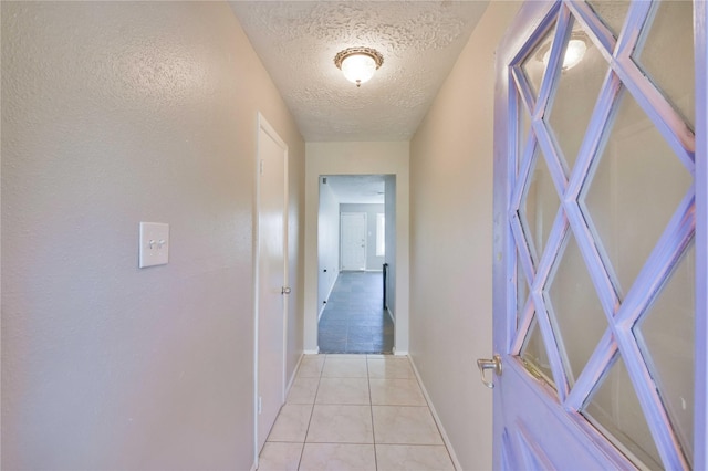 hallway with light tile patterned flooring and a textured ceiling