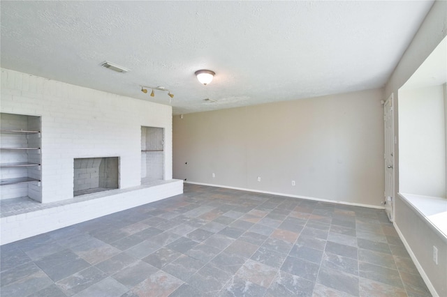 unfurnished living room with a textured ceiling and a brick fireplace