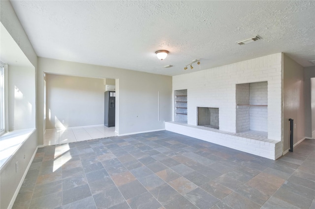 unfurnished living room featuring a fireplace, a textured ceiling, and rail lighting