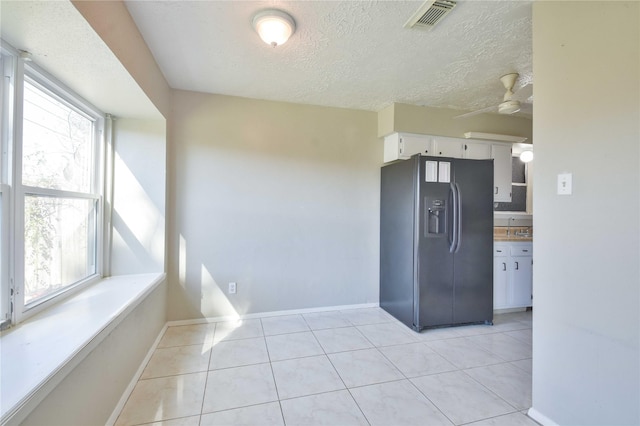 kitchen featuring black refrigerator with ice dispenser, ceiling fan, light tile patterned floors, a textured ceiling, and white cabinetry