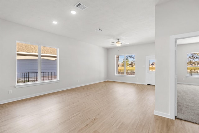 unfurnished room with a wealth of natural light, ceiling fan, and light hardwood / wood-style flooring