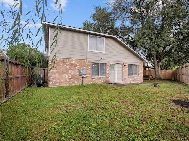 rear view of house featuring a lawn and central air condition unit