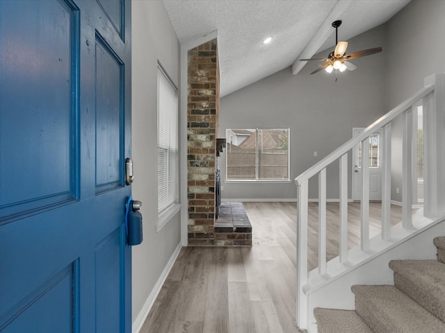 foyer with hardwood / wood-style floors, vaulted ceiling with beams, ceiling fan, and a textured ceiling