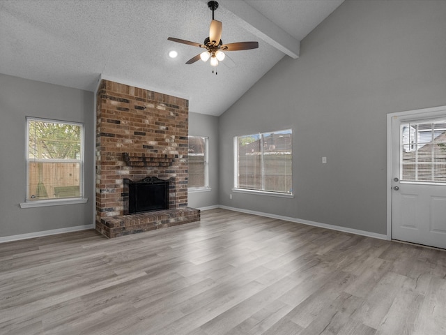 unfurnished living room featuring high vaulted ceiling, ceiling fan, a textured ceiling, a fireplace, and light hardwood / wood-style floors