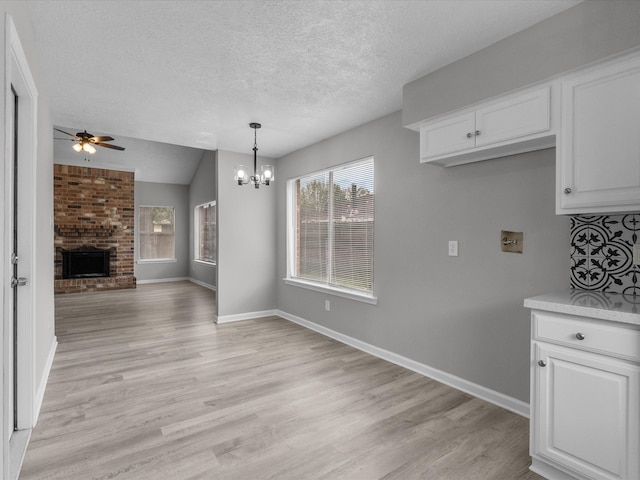 kitchen featuring a brick fireplace, white cabinetry, and light hardwood / wood-style flooring