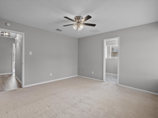 unfurnished room featuring ceiling fan, light colored carpet, and a textured ceiling