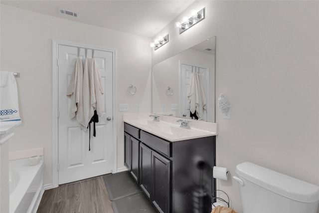 bathroom with hardwood / wood-style flooring, vanity, toilet, and a bath