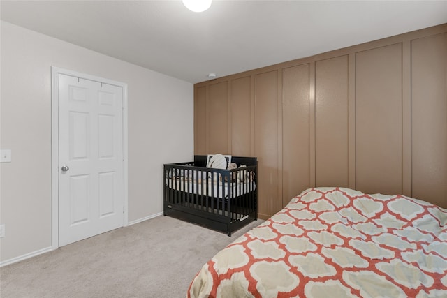 bedroom featuring light colored carpet and a nursery area