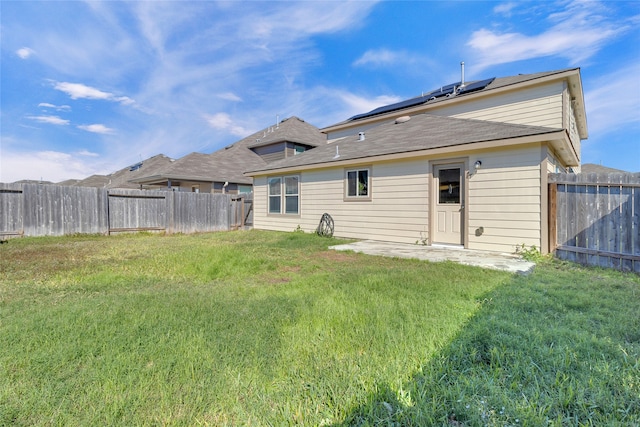 rear view of house with a yard and solar panels