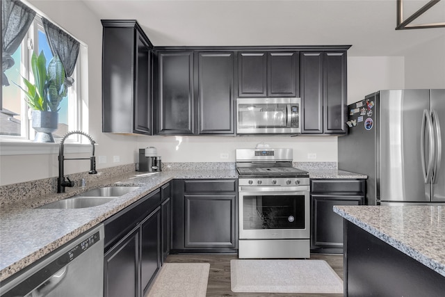 kitchen featuring stainless steel appliances, light stone counters, dark hardwood / wood-style floors, and sink