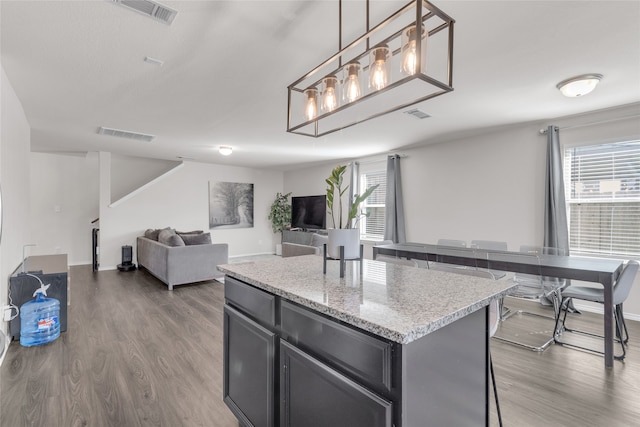 kitchen with pendant lighting, a kitchen island, a wealth of natural light, and dark wood-type flooring