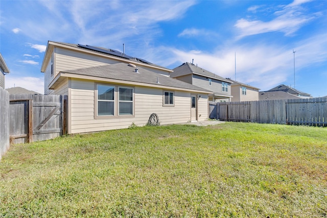 back of house featuring a yard and solar panels