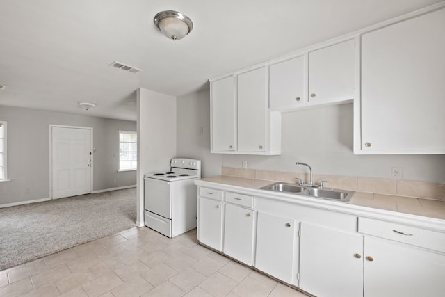 kitchen featuring light carpet, sink, white electric stove, white cabinets, and washer / clothes dryer