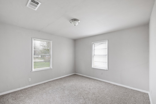 empty room with a wealth of natural light and carpet