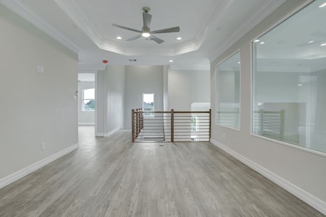 spare room featuring ceiling fan, a raised ceiling, ornamental molding, and light hardwood / wood-style flooring