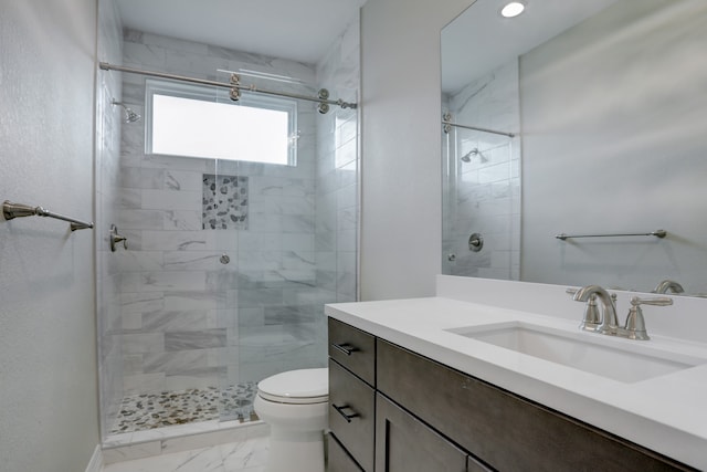 bathroom featuring toilet, vanity, and tiled shower