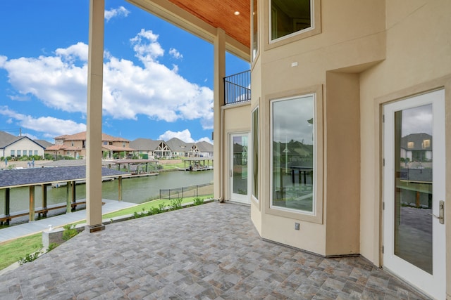 view of patio / terrace with a dock, a balcony, and a water view