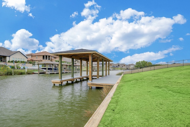 view of dock with a lawn and a water view