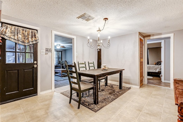 1215 Esther St, Kemah, TX 77565 - dining space featuring a textured ceiling, a chandelier, baseboards, and light tile patterned flooring