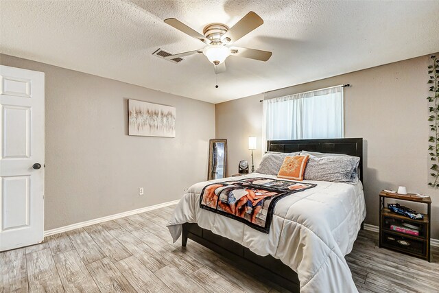 bedroom featuring wood-type flooring, a textured ceiling, and ceiling fan