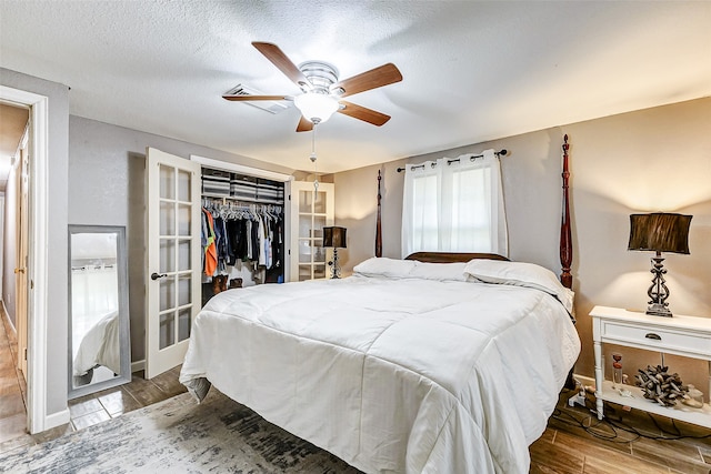 bedroom with ceiling fan, light hardwood / wood-style floors, a textured ceiling, and a closet