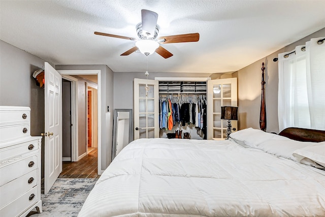 bedroom with ceiling fan, a closet, dark wood-type flooring, and a textured ceiling