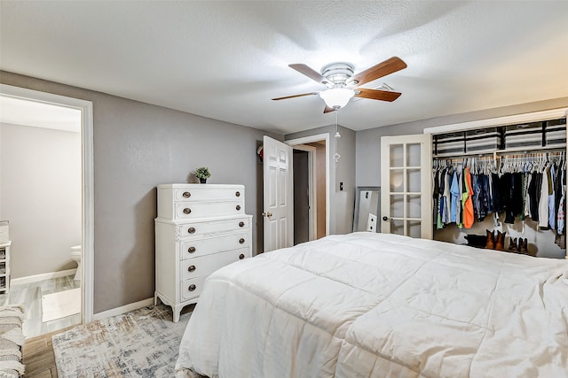 bedroom featuring ceiling fan, light wood-type flooring, a textured ceiling, connected bathroom, and a closet