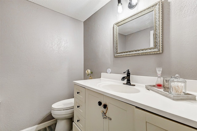 bathroom featuring vanity, toilet, and a textured ceiling