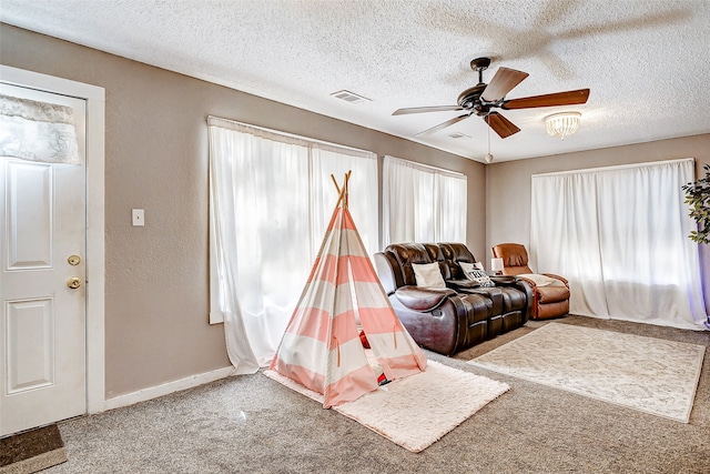 living room featuring carpet, a textured ceiling, and ceiling fan