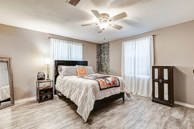 bedroom with a textured ceiling, light hardwood / wood-style floors, and ceiling fan