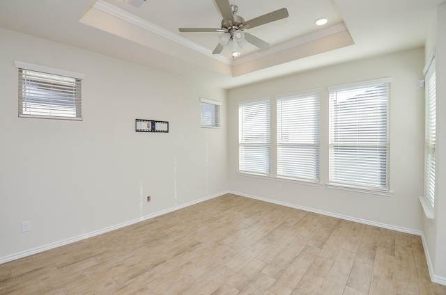 empty room featuring a tray ceiling, light hardwood / wood-style flooring, ceiling fan, and crown molding