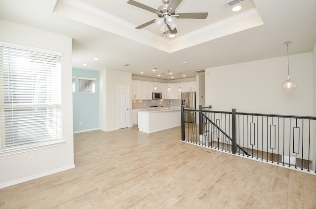 unfurnished living room with ceiling fan, light wood-type flooring, crown molding, and a tray ceiling