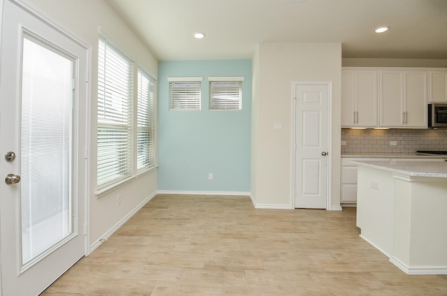 kitchen with tasteful backsplash, white cabinets, and light wood-type flooring