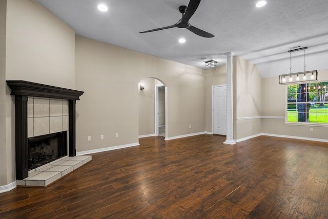 unfurnished living room with dark hardwood / wood-style floors, ceiling fan, lofted ceiling, and a fireplace